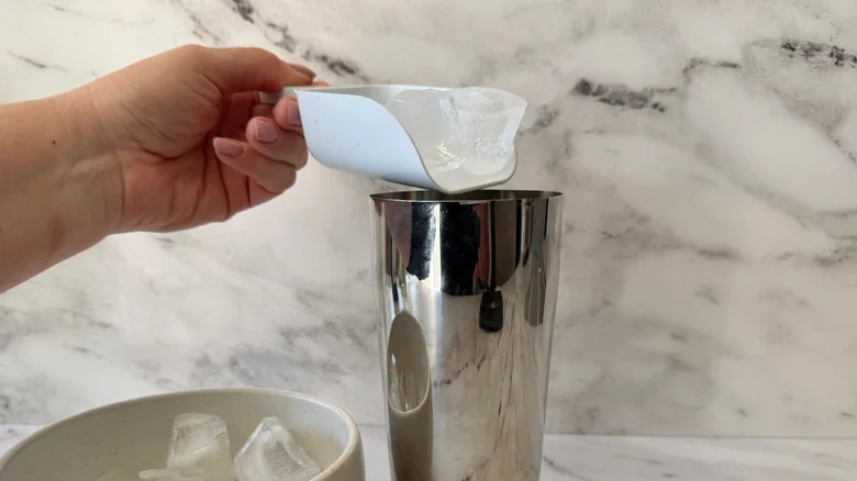 Hand scooping ice into cocktail shaker