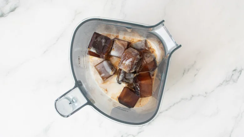 Coffee ice cubes, milk, and caramel in blender