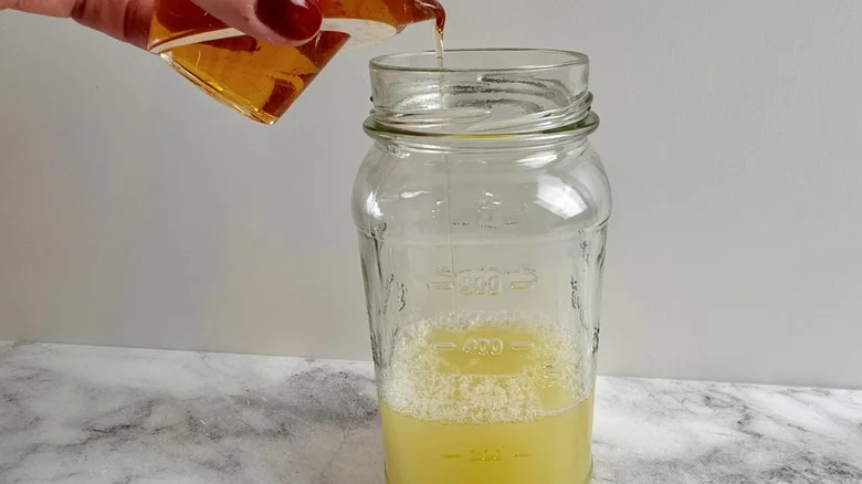 hand pouring liquid into a jar of lime juice