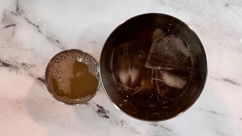 metal tumbler full of liquid next to a cup of liquid
