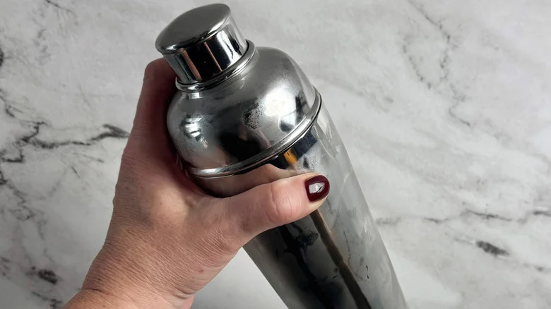 hand holding a lidded metal tumbler