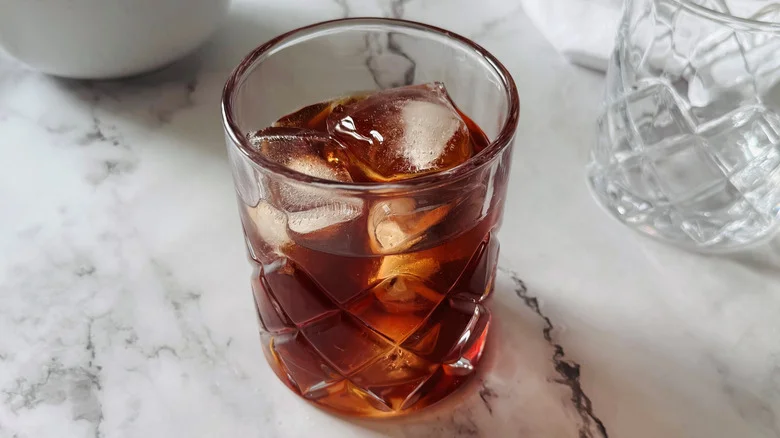 drinking glass filled with ice and brown liquid