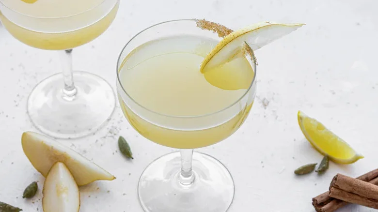 A light yellow martini with a partial brown sugar rim and a slice of pear garnish.