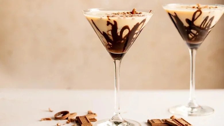 Two chocolate martinis with chocolate drizzle inside glass.