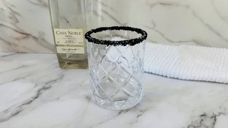 drinking glass with a black salt rim in front of a folded towel