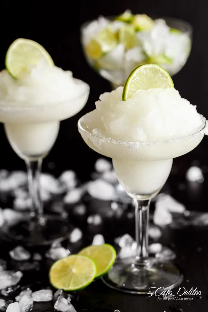 Two glass of Frozen Margarita Slushies topped with a round slice of lime in each glass. 
